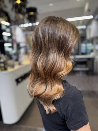 Precizní balayage v teplejších, přirozených tónech s plynulým přechodem, doplněná čistým střihem a elegantními glam vlnami...